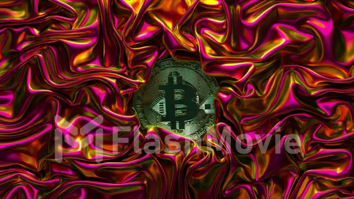 A fabric of metallic neon pink is wrinkled around the bitcoin. Shiny fabric. Cryptocurrency. Creases in fabric. Drapery