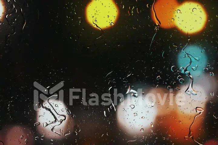 Raindrops on a car window with beautifully blurred background of street traffic lights