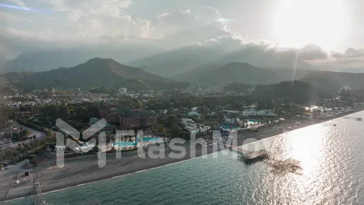 Aerial drone view of the city on the coast. Sunset. Green mountains. Residential houses. Photography