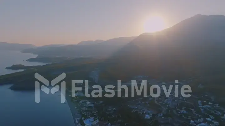 Aerial drone view of a tourist town by the sea. Sunset against the backdrop of a mountain landscape.