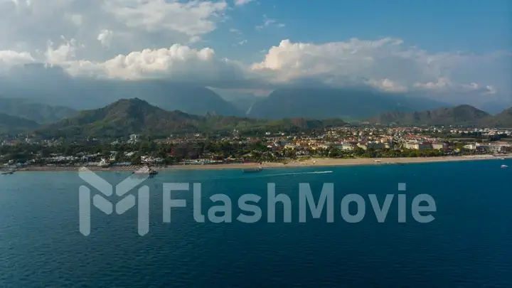 View from the sea to the coastal city. Sunny day. Green mountains. Aerial drone view. Landscape. Coastline. Boats.