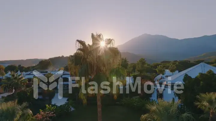 Aerial drone view of the hotel at sunset. Palms. Mountain landscape on the background. Beautiful landscape