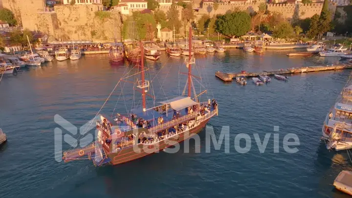 Aerial drone view of a tourist ship sailing into the bay. Harbor. Historic city in the background.