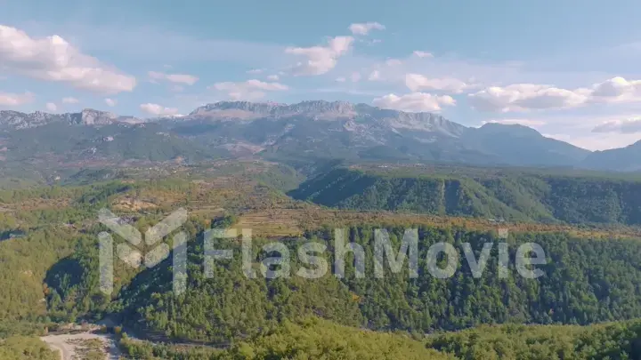 Top view. Aerial drone view of flight over the hills. Mountain landscape. Blue sky white clouds. Green trees.