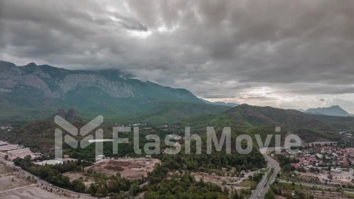 Drone video 4k footage. Flight over a residential area at the foot of the mountains. Green trees. Highway. Gray clouds.