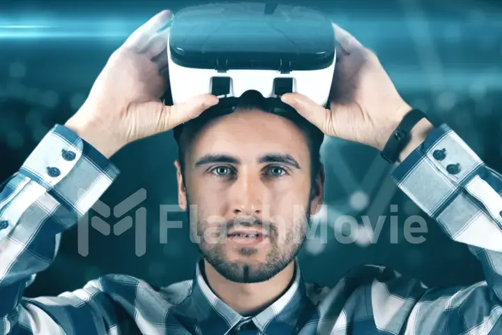 A young man with a beard in glasses of virtual reality on a technological background