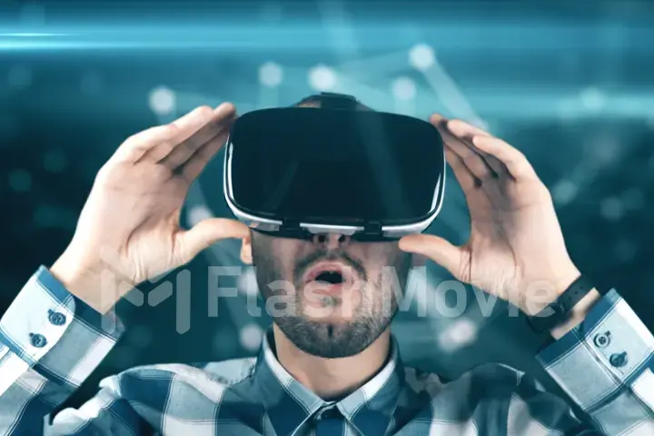 A young man with a beard in glasses of virtual reality on a technological background