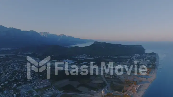 Aerial drone view of a tourist town by the sea. Sunset against the backdrop of a mountain landscape. Photography