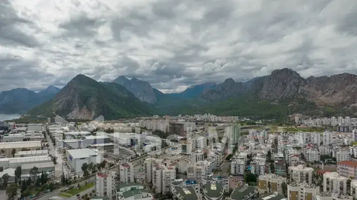 Top view of the big city. Residential houses. Urbanization. Green mountains and clouds in the background. Photography