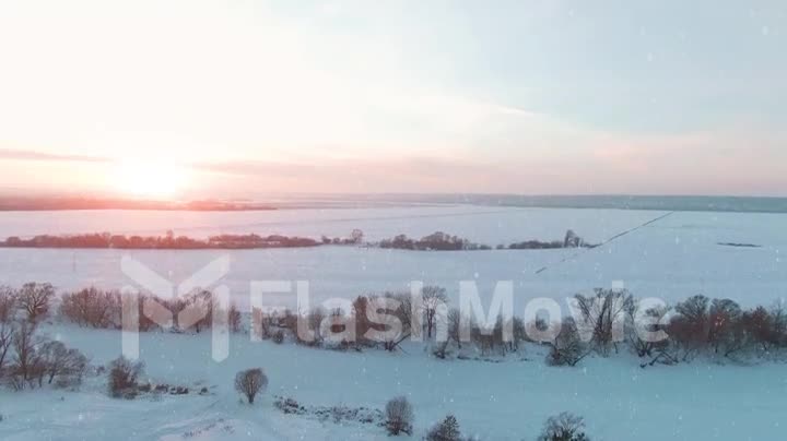 4k Aerial view, falling snow in a winter sunny day at sunset