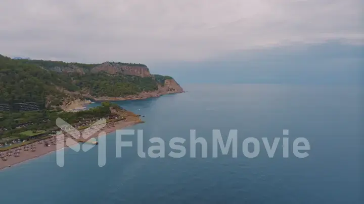 Natural landscape. Aerial drone view of a beach in a blue bay. Rocky coast. Green trees on the rocks.