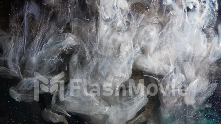 Abstract bronze paint mixed with different multi-colored paints in water in slow motion. Inky cloud swirling flowing underwater. Abstract smoke explosion