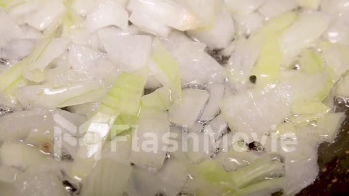 Close-up onion frying in a pan in oil in slow motion