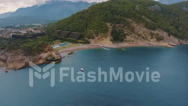 Natural landscape. Aerial drone view of a beach in a blue bay. Rocky coast. Green trees on the rocks.