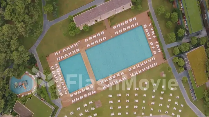 Aerial drone view of the hotel territory. Top view. Swimming pool, palm trees, sun loungers. Holidays at the resort