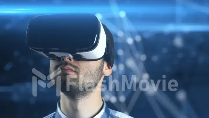 A young man with a beard in glasses of virtual reality on a technological background