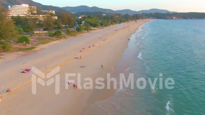 Sunset on Karon beach, people swim in the sea and sunbathe, resort beach. A few days before closing beaches due to quarantine covid-19. Aerial 4k footage