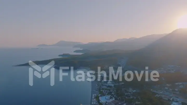 Aerial drone view of a tourist town by the sea. Sunset against the backdrop of a mountain landscape.