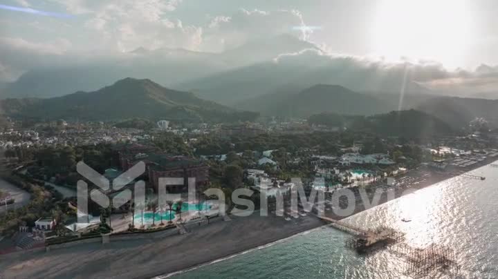 Aerial video footage of a beautiful cityscape on the coastline. Green mountains in the background. Timelapse