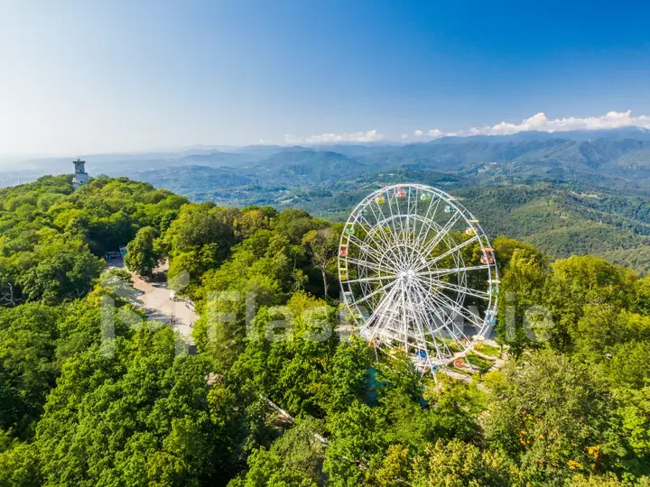 Beautiful mountain landscape with a ferris wheel and an old castle. Aerial view