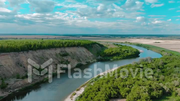 Beautiful aerial 4k view over the curving river along the fields and forest