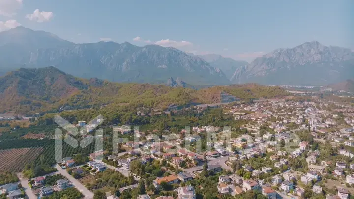 Top view of small resort town. Hotels, houses and roads. Green hills around. Rooftops. Panorama.