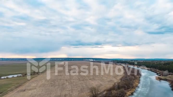 Drone lapse beautiful countryside scenery, cultivated green fields and colorful sunset horizon with yellow blue sky fast moving clouds, time lapse up motion