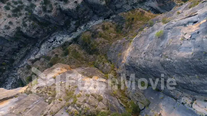 Aerial drone view of dry mountain river. Stone gorge. Green plants on the rocks. Beautiful landscape.