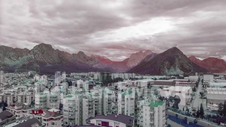 Top view of the big city. Color correction. Mountains and clouds in the background. Road intersection. Timelapse