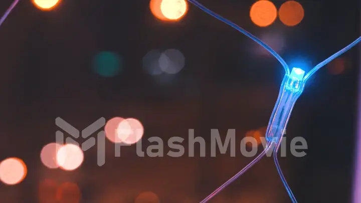 Christmas garland with colorful lights by the window against the background of the city and the movement of cars, close-up. Blurred Christmas lights. Bokeh