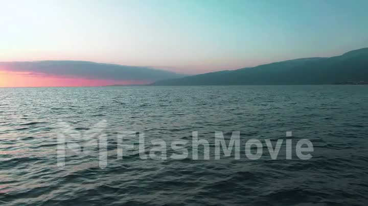 Aerial 4k view. Stunning sunset sun over the sea. Beautiful cinematic scene. Golden sun sets over the horizon, flying above the surface of the water in slow motion