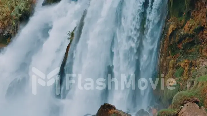 Nature concept. White foamy waterfall flows from the cliff. Close-up drone view. The power of the elements.