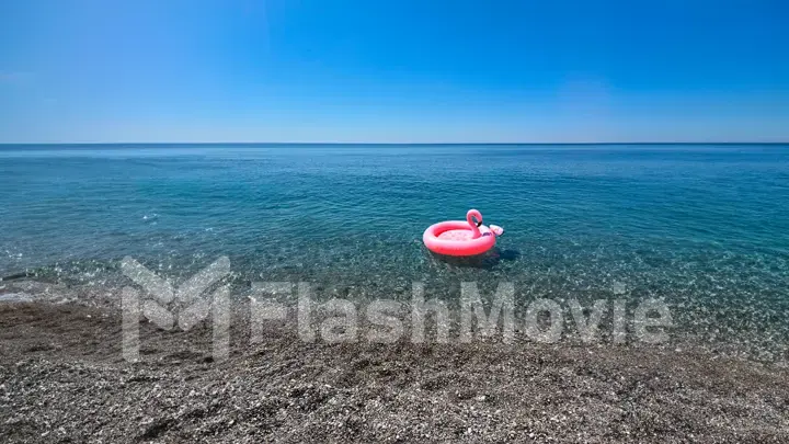 Beach holiday concept. A large inflatable pink flamingo floats in the sea. Blue sky and clear water. Photo