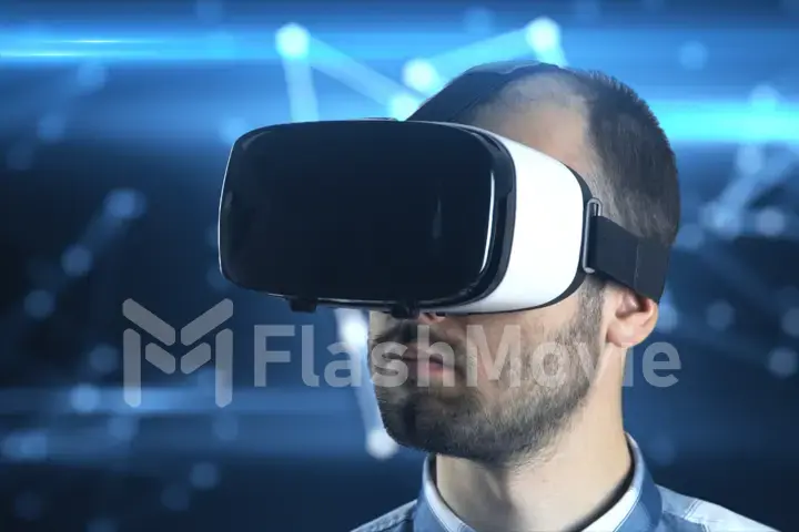 A young man with a beard in glasses of virtual reality on a technological background