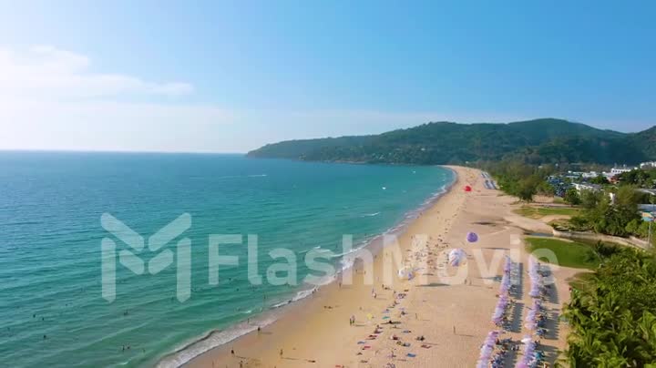 Aerial 4k view flying over tropical blue ocean towards beautiful green mountains and white sandy beach. Thailand. Phuket. Karon beach. Palms beach. Island top view. Beautiful resort place.