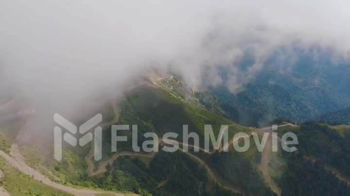Flight over the tops of green mountains. Drone video 4k footage of green mountains and clouds. Foggy landscape