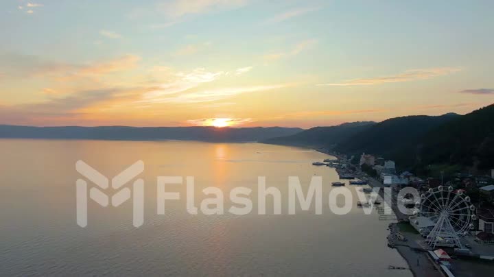 Sunset over the sea. Coastline. Seascape. Aerial video footage from a drone. Water surface. Buildings on the coast.