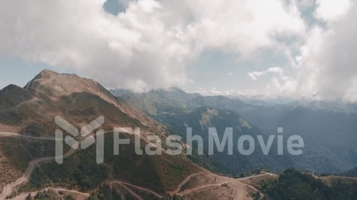 Video filming from a drone of a mountain landscape. Green hills Cloudy sky. Mountain roads. Human and nature