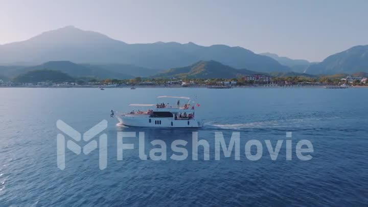 The yacht is sailing fast on the blue sea against the backdrop of a mountain landscape. Seascape. Drone video footage.