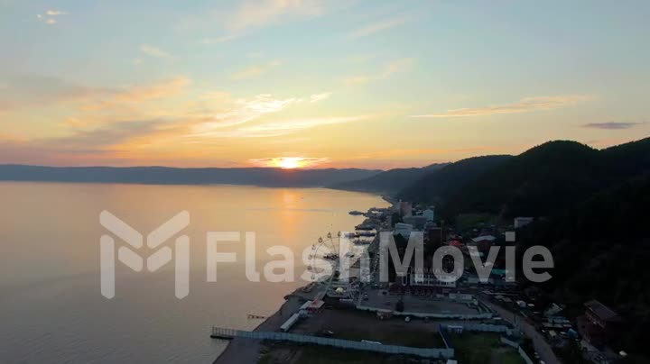 Sunset over the sea. Coastline. Seascape. Aerial video footage from a drone. Lake Baikal. Buildings on the coast.