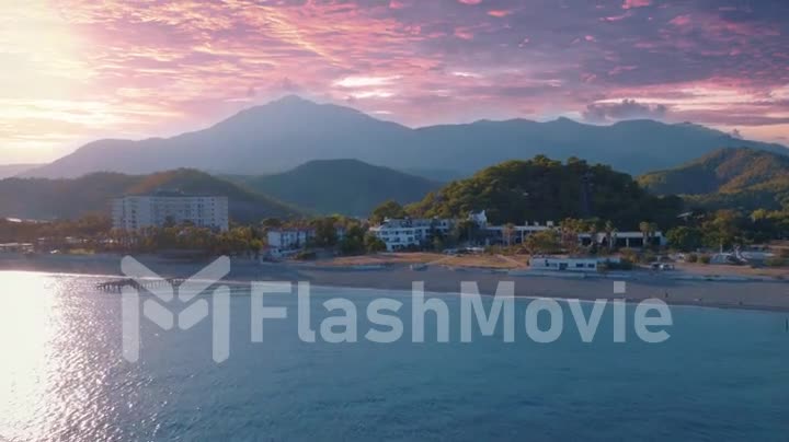Beautiful sunset. Seascape. Coast and mountains in the background. Aerial footage from drone flight over blue sea