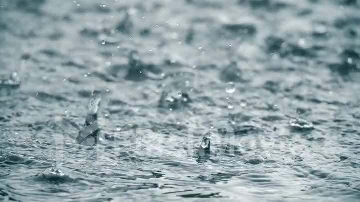 Rain falling to the surface in slow motion, drops of water spray in different directions