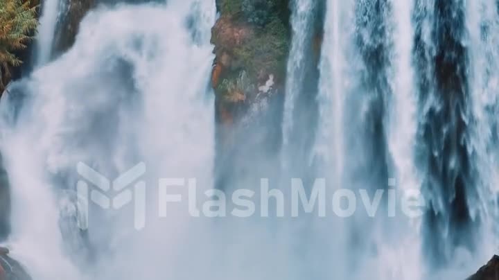 Drone video footage of a natural waterfall close-up. Spray. Foam. Green vegetation on the rocks. Natural element.