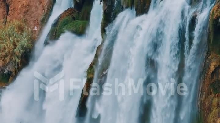 Waterfall from a cliff close-up. Drone video footage. A stormy stream of water falls down. Nature background