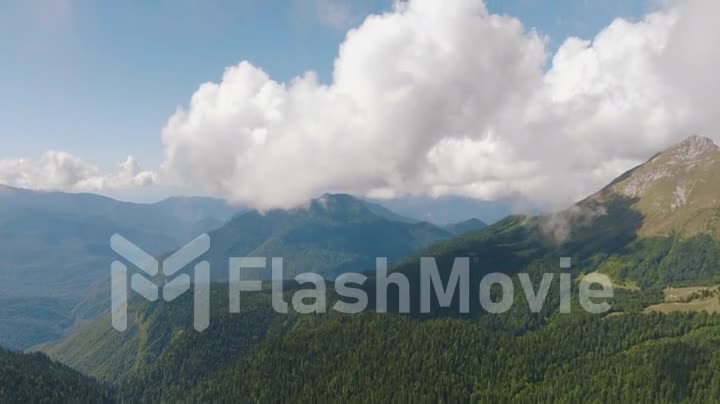 Drone video 4k footage of a mountain landscape. Big clouds over the mountains. Fog. Green Forest. View from above