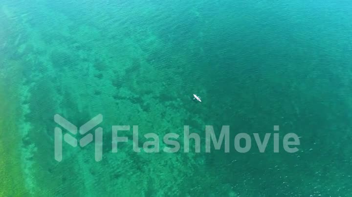 Aerial footage of a white boat on the water of lake. Pure water. Rowing. View from above. Drone footage.