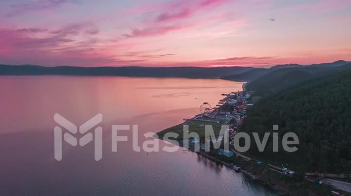 Aerial footage of flight over the sea at pink sunset. Hyperlapse. Coast. Top view. Clouds. Drone footage.