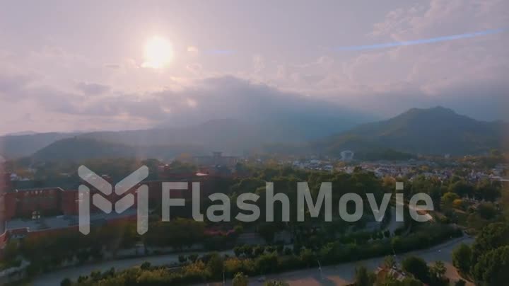 Human and nature concept. Aerial drone footage. Small town at the foot of the mountain. Green trees. Mountain landscape
