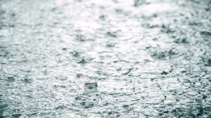 Rain falling to the surface in slow motion, drops of water spray in different directions