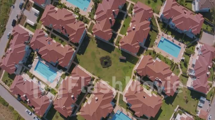 A view from above of the territory. Bungalow rooftops, swimming pools, green lawns and palm trees. Aerial video footage